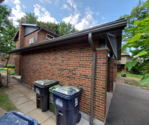 eavestrough assessment on brick home with downspout and roofline inspection