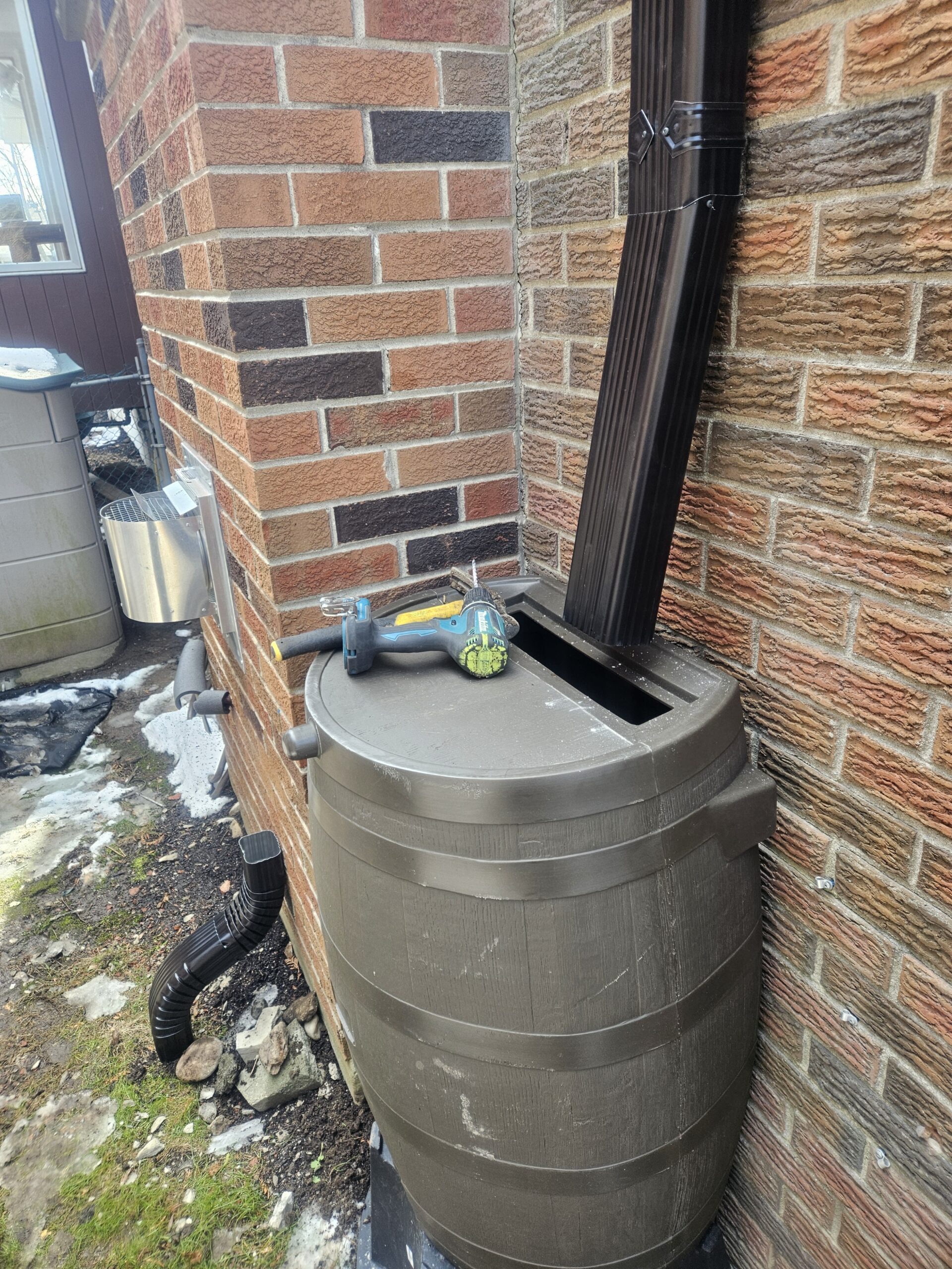 rain barrel connected to downspout on brick home in Toronto