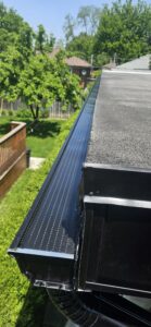 Black gutter guard installed along backyard roofline