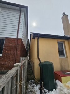 rain barrel water collection system installed at rear of home