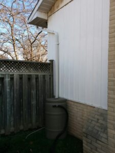 rain barrel connected to aluminum downspout on residential home
