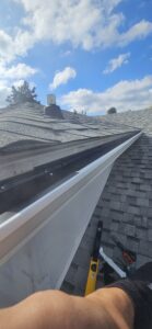 Gutter guard installed beneath shingles on sloped roof